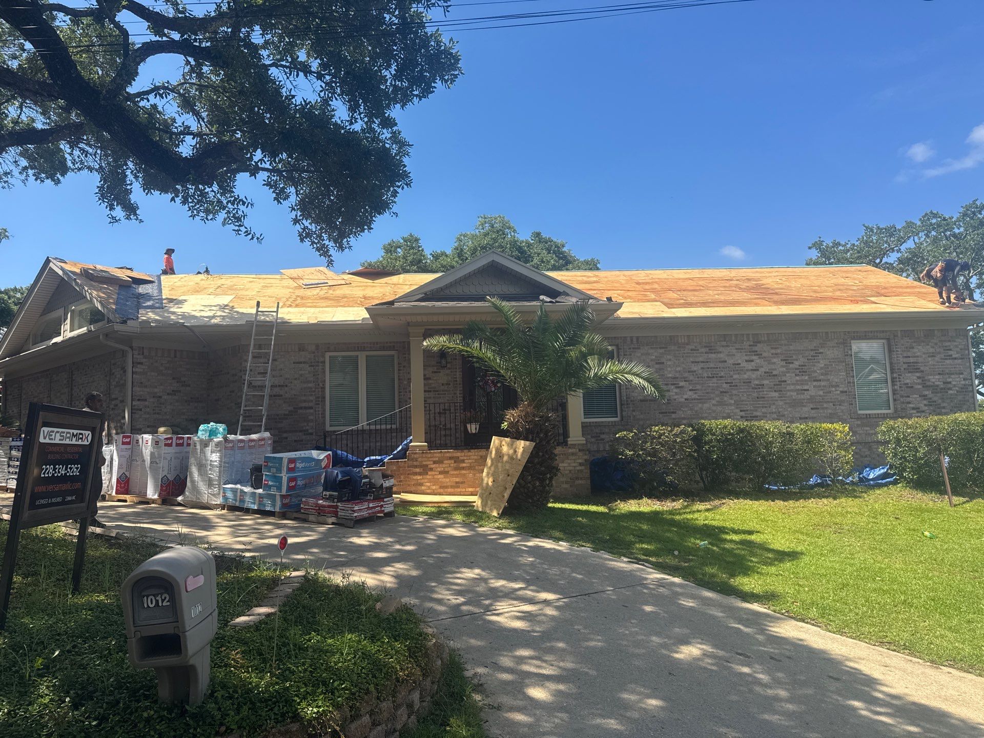 VersaMax crew re-roofing a brick home with pallets of GAF shingles on site