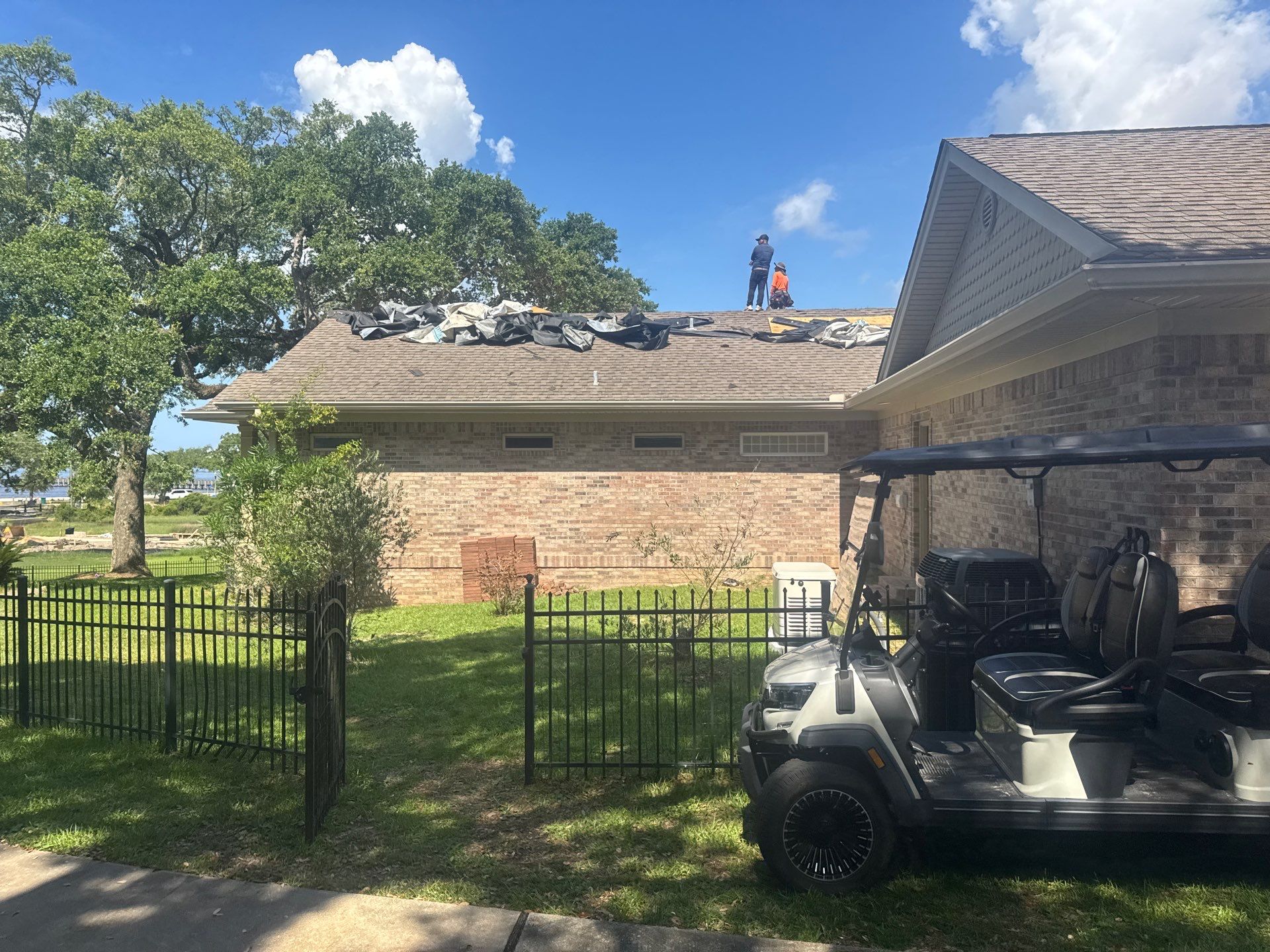 Crew tearing off old shingles with debris bundled on tarps along the roof