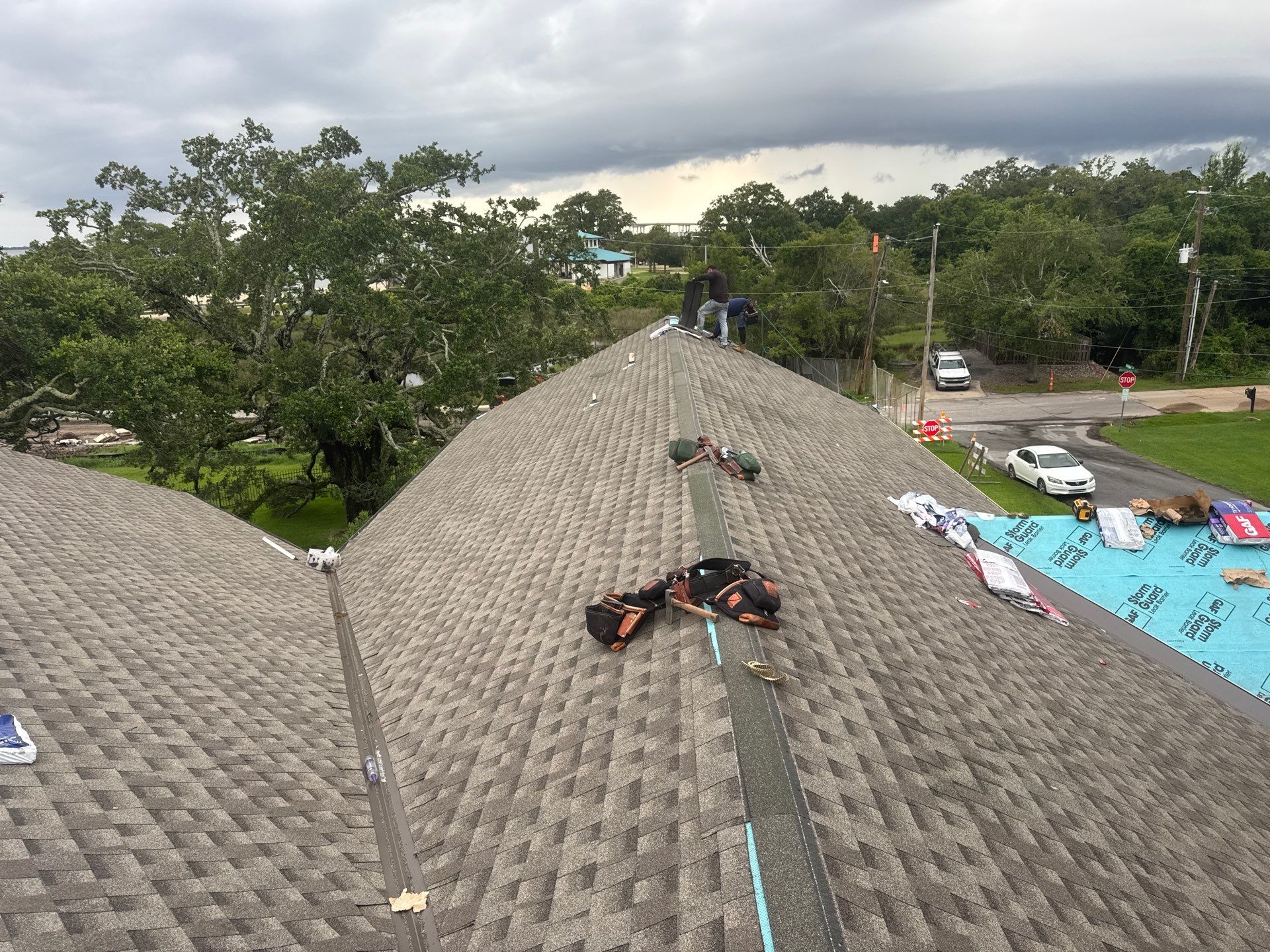 Completed architectural shingle roof at dusk with stormy Gulf Coast sky overhead