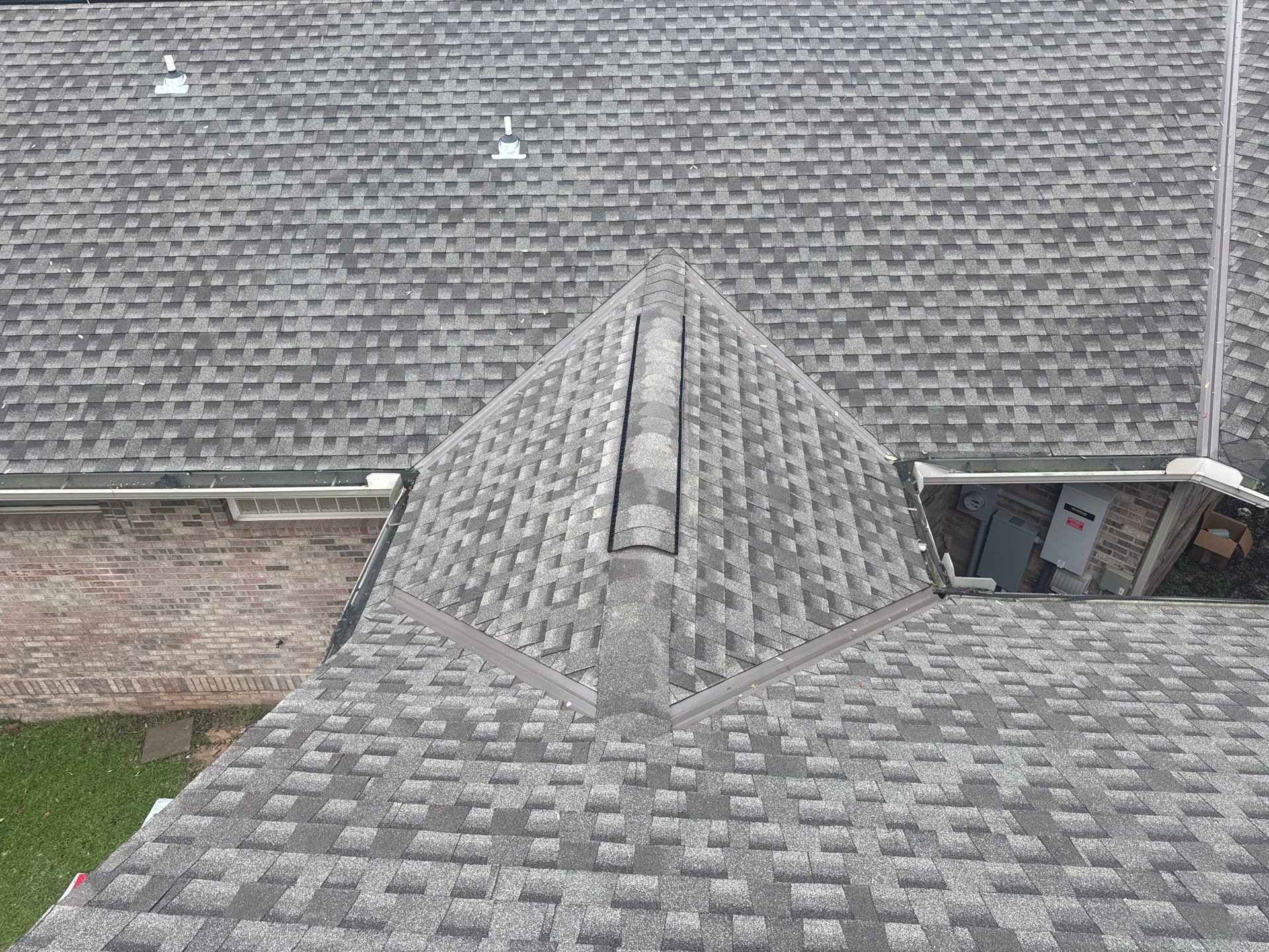 Overhead view of an asphalt shingle roof with hips, cut valleys, and ridge cap on a GD Construction re-roof