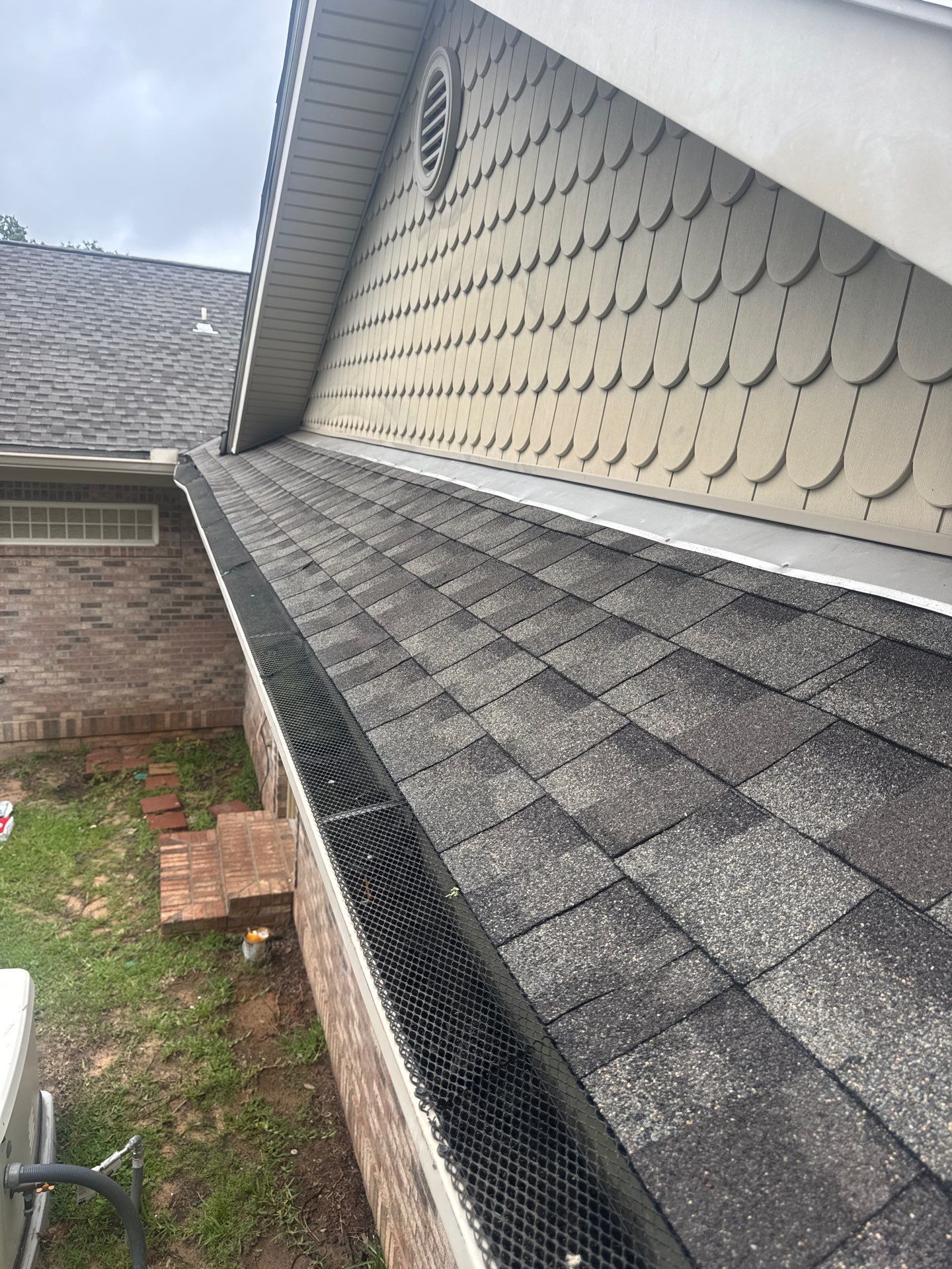 Finished shingle roof with wall flashing tied into siding and gutter guard installed