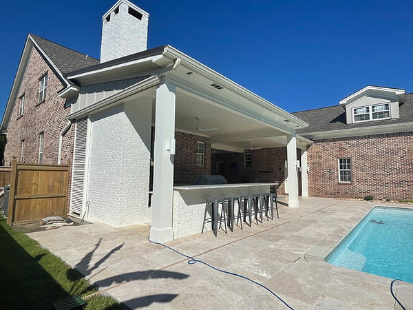 Covered outdoor living area with wrapped posts, bar seating, and pool